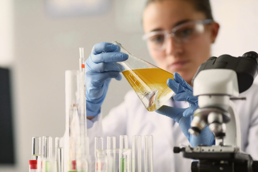 Researcher examining a yellow liquid in a laboratory flask