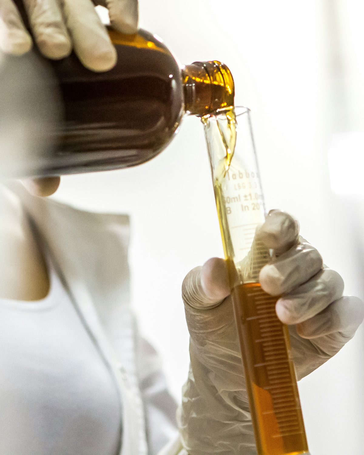 Amber laboratory liquid being poured into a measuring tube
