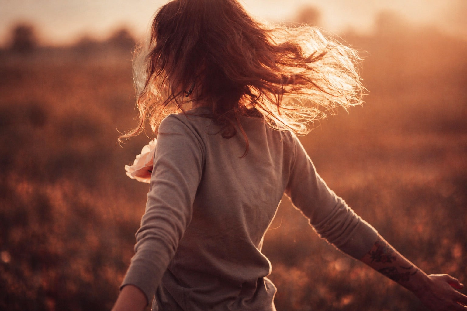 Woman walking through a field at sunset