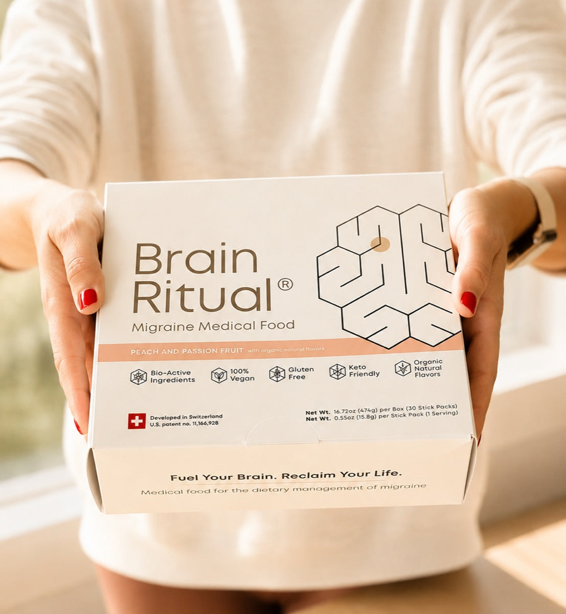 Hands holding a Brain Ritual Migraine Medical Food box in warm light