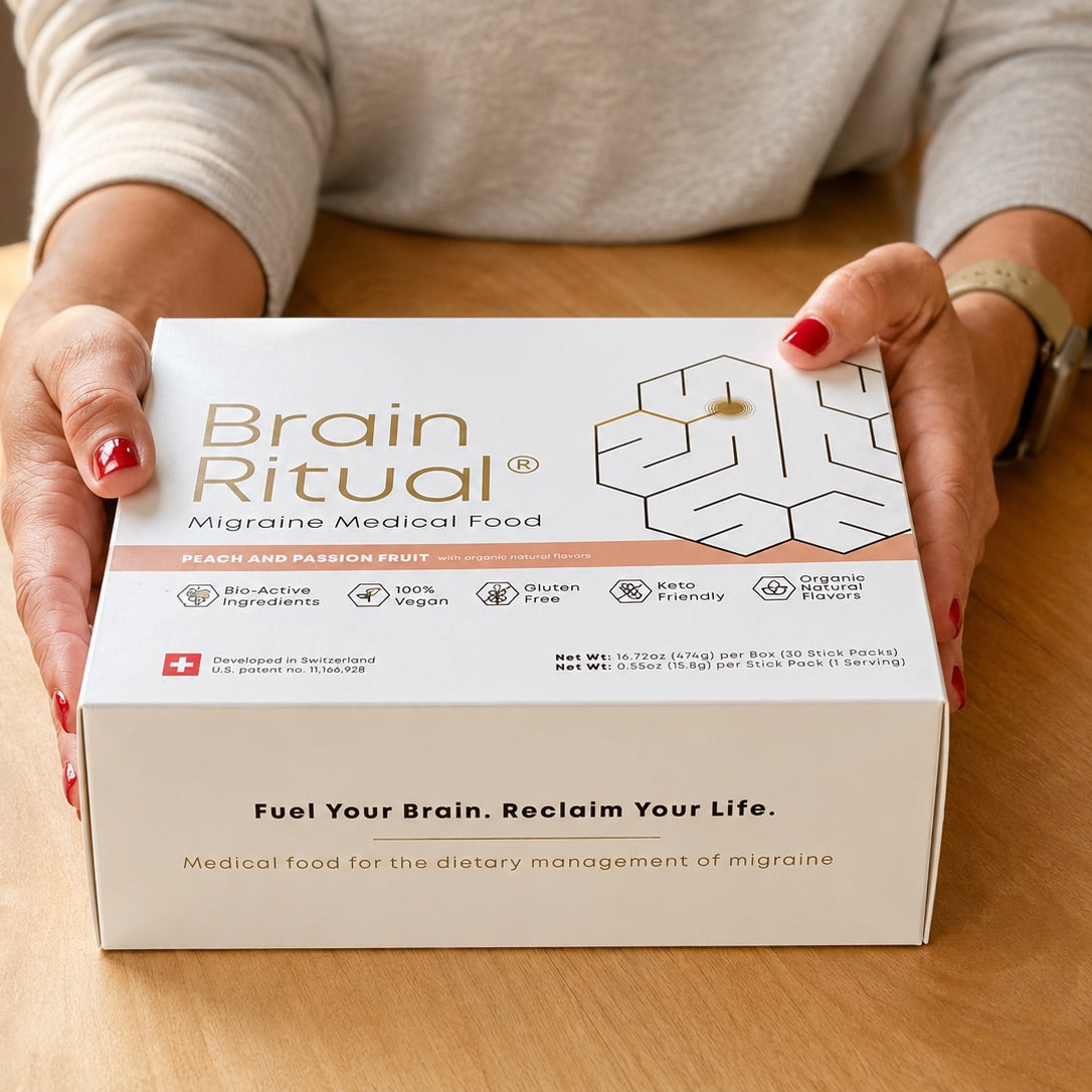 Hands holding a Brain Ritual Migraine Medical Food box on a wooden table