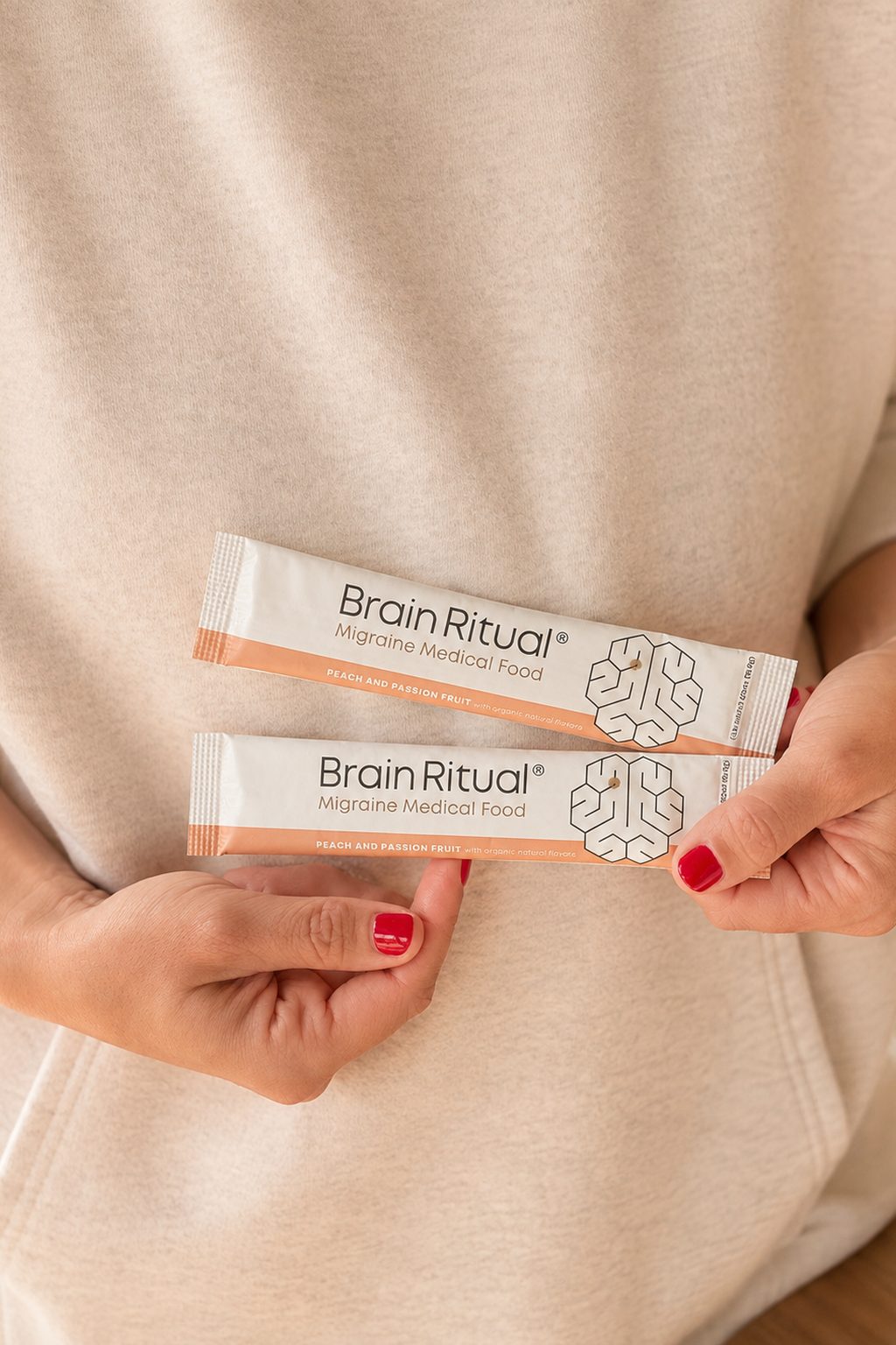Hands holding two Brain Ritual Migraine Medical Food stick packs