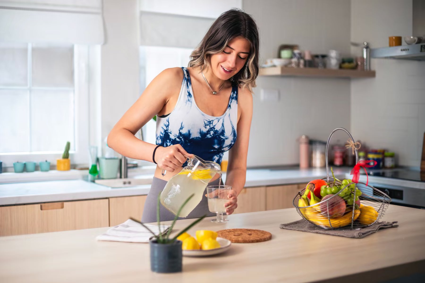 Woman pouring a drink in a bright kitchen