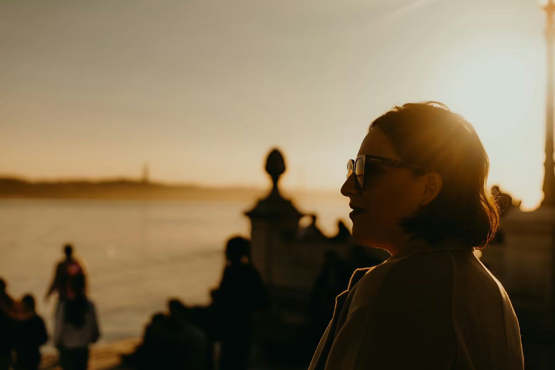 Person in sunglasses at sunset near the water
