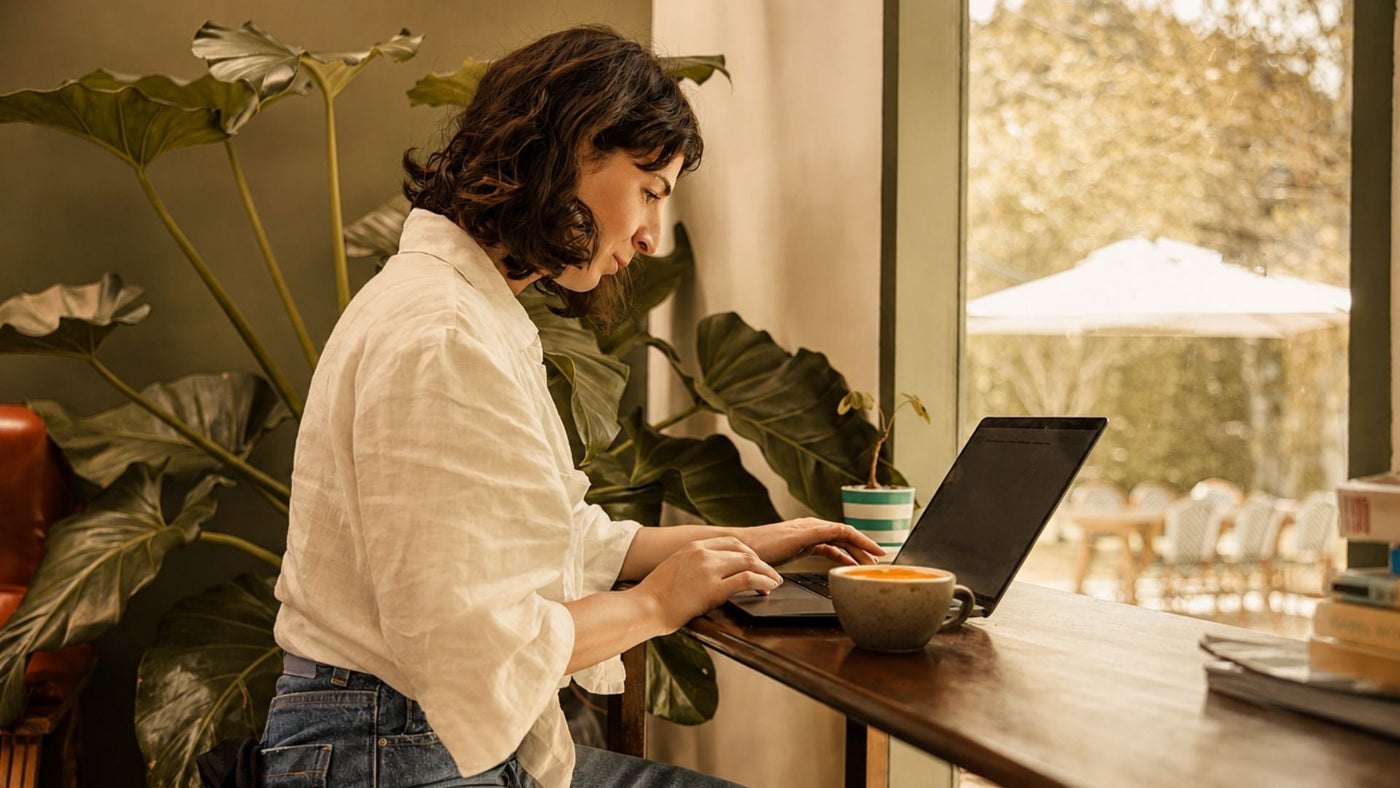 Woman researching on a laptop in a light airy space for an article on HRT for migraine