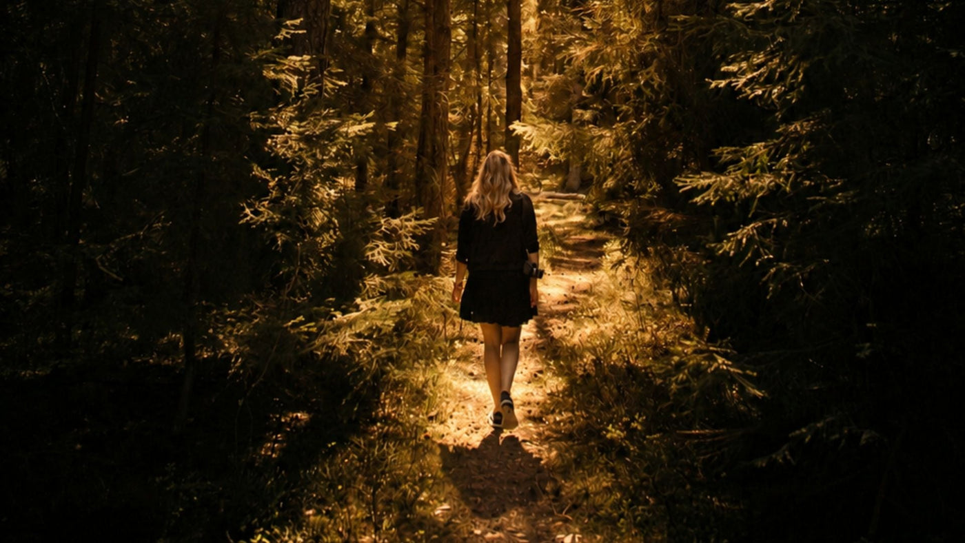 Woman walking in the forest at golden hour, to represent how a bug bite could trigger a migraine article