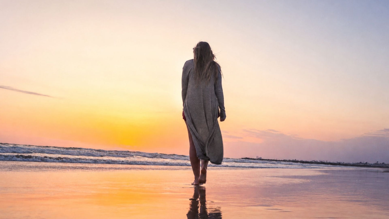 Woman walking at a soft sunset on the beach for an article on migraine phases