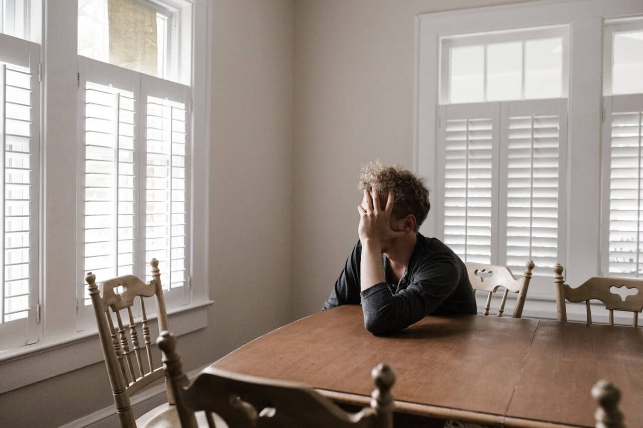 Man sitting at table with hand on face looking exhausted