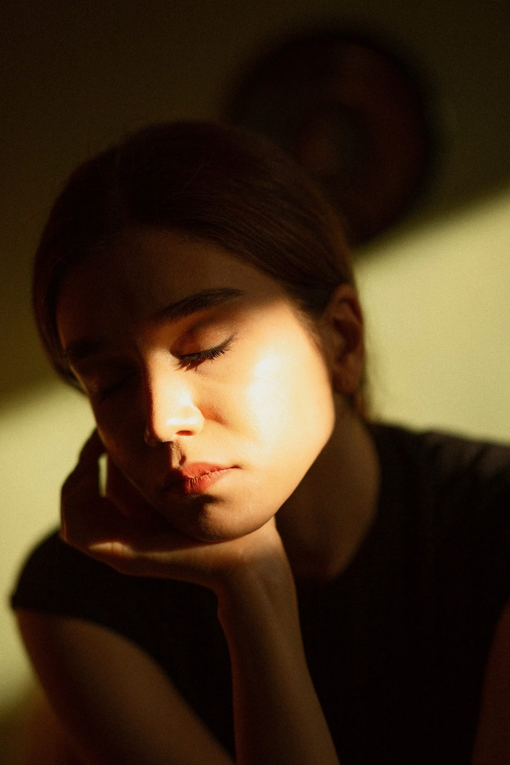Woman resting her head in shadow and warm light