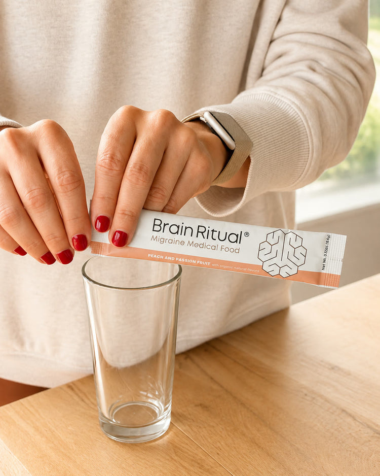 Hands emptying a Brain Ritual stick pack into a glass