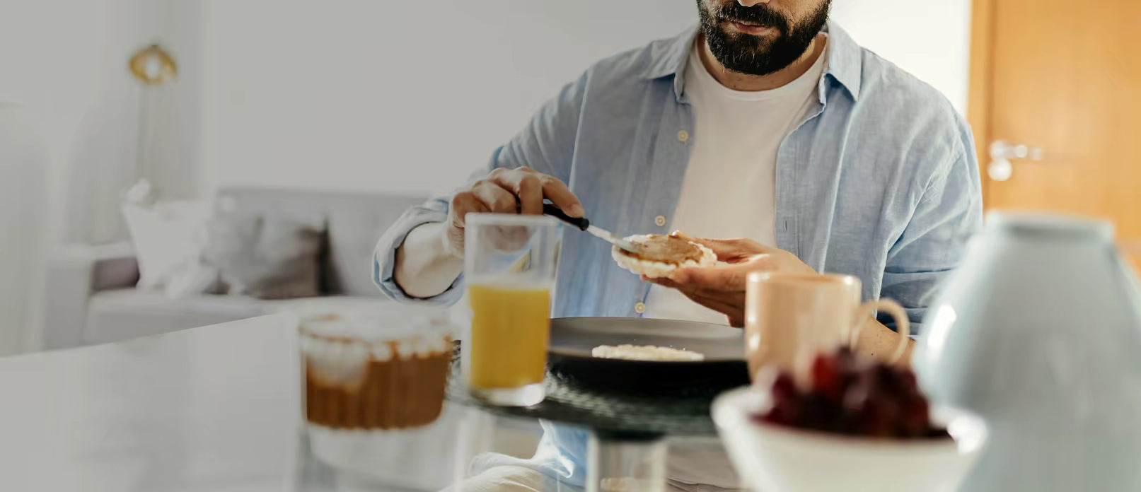 Man spreading food on a cracker at a breakfast table
