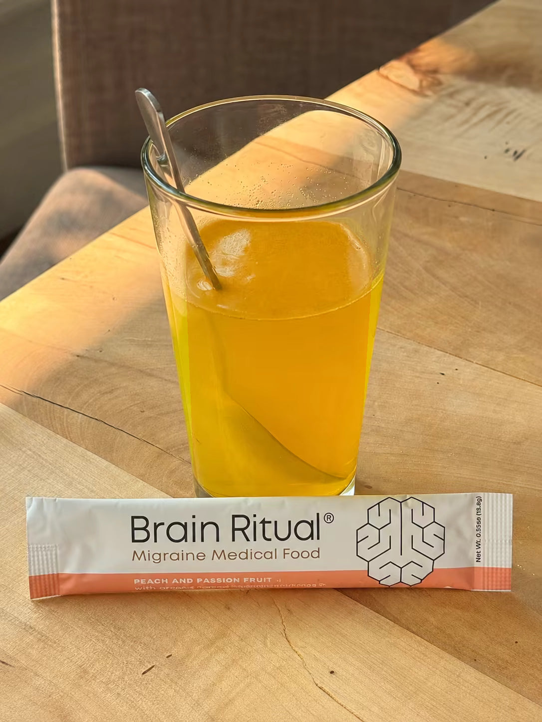 Brain Ritual drink with a peach and passion fruit stick pack on a wooden table
