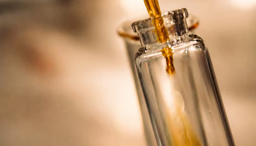 Golden liquid pouring into a lab vial