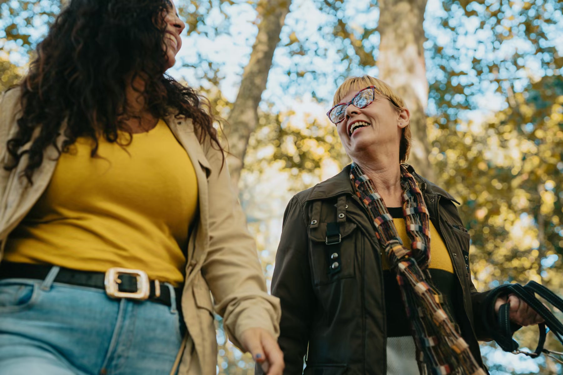 Two women walking outdoors in dappled sunlight