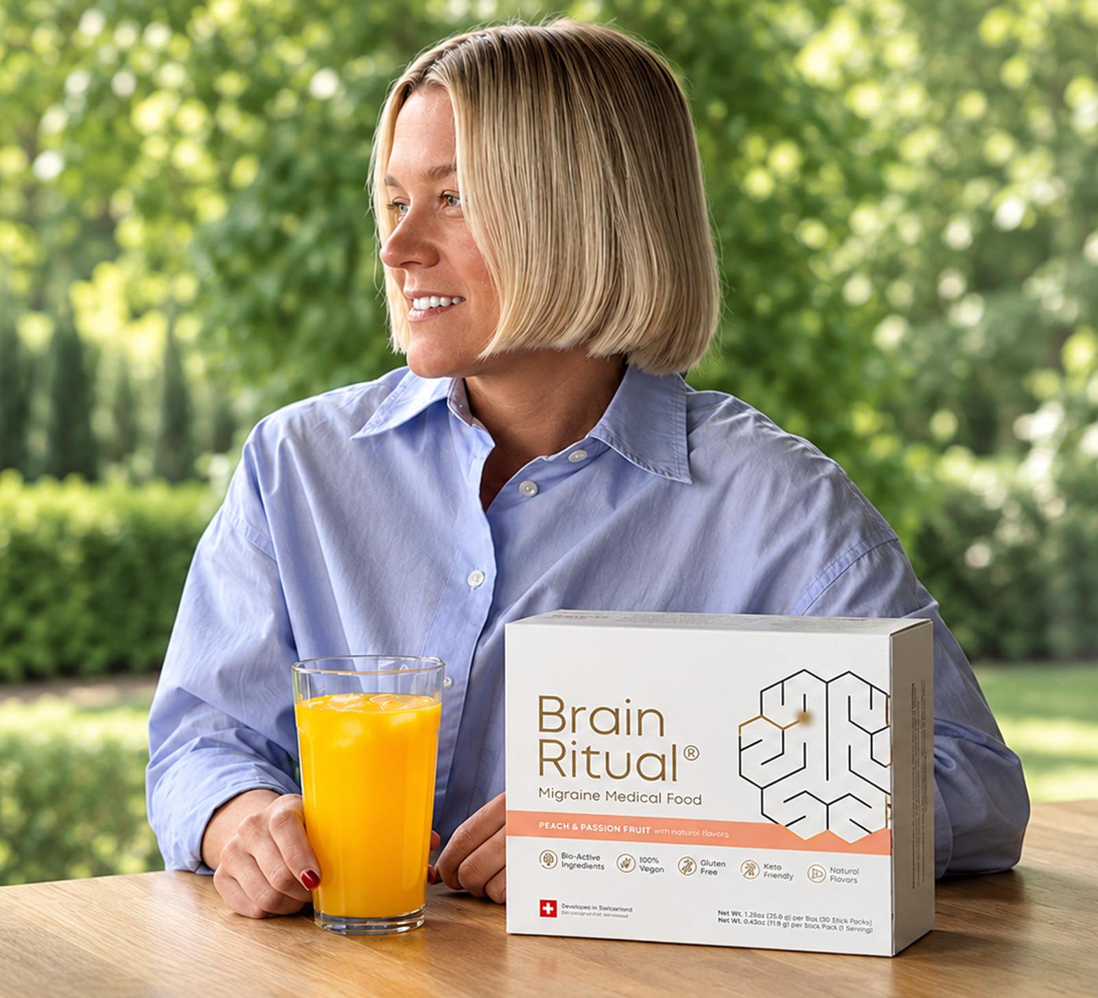 Woman at a garden table with a glass of Brain Ritual and a box of Brain Ritual Migraine Medical Food