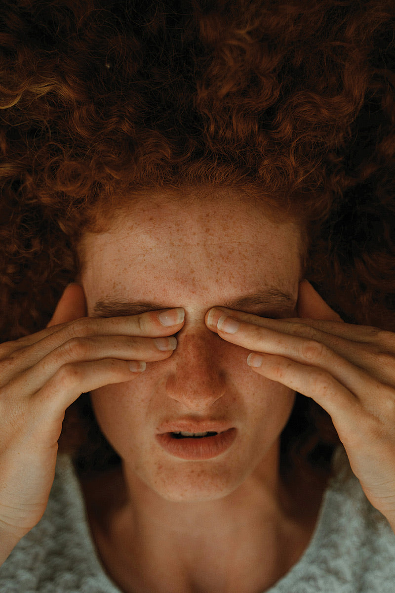 Person pressing their fingers to closed eyes during a migraine